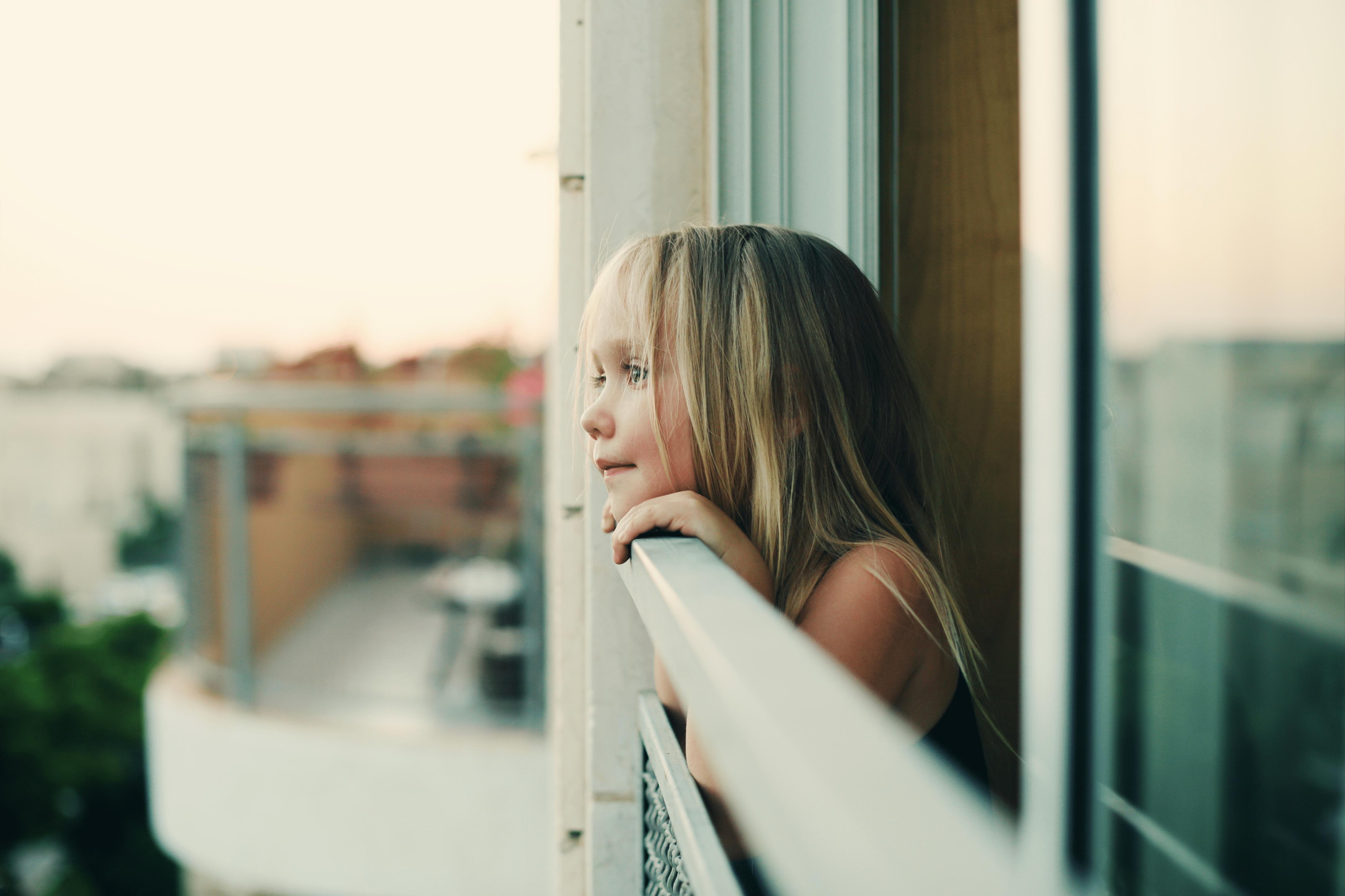 Une jeune qui regarde par dessus un balcon